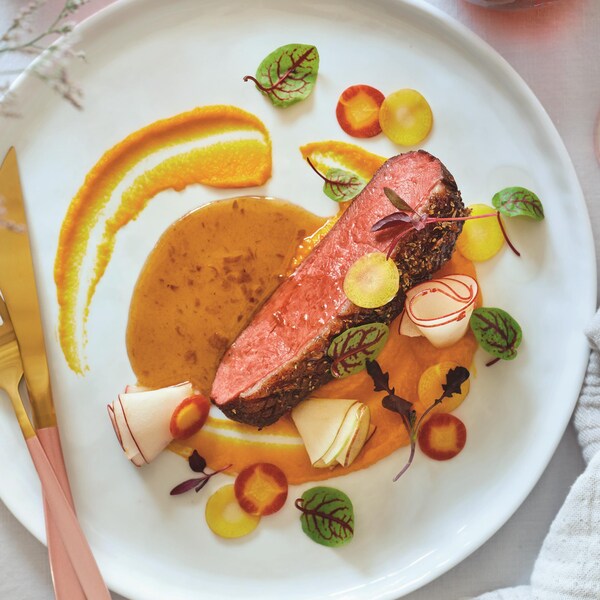 Du magret de canard dans une assiette avec une sauce au miel et aux épices et une purée de carottes.