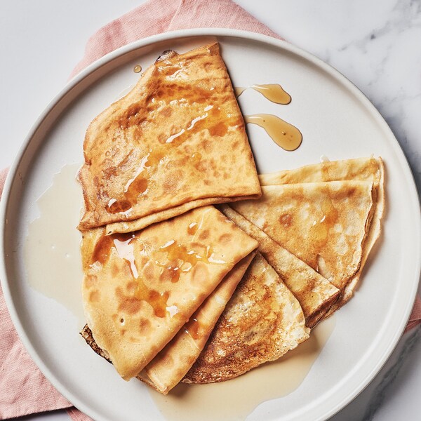 Deux assiettes de crêpes servies avec un contenant de sirop d'érable.