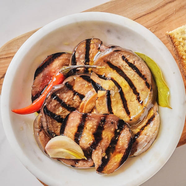 Des aubergines grillées et marinées dans un bol avec du pain.