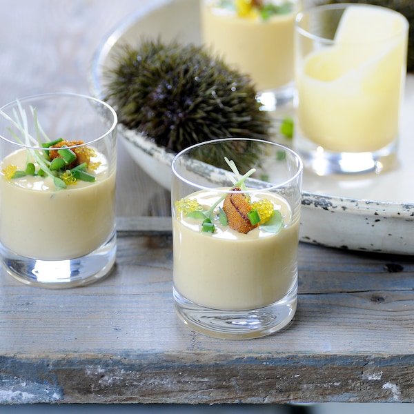 Deux verres remplis de smoothie d'oursin couleur crème et décorés d'une gonade d'oursin et d'herbes ciselées.