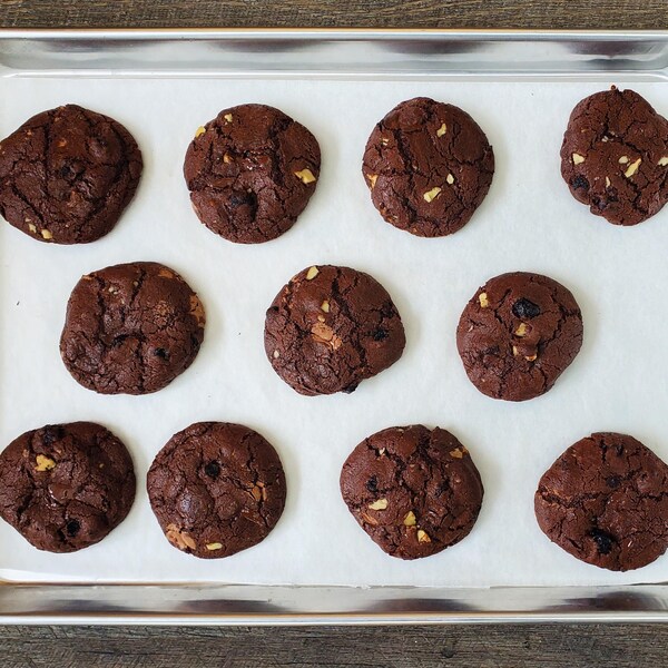 Une plaque de cuisson avec des biscuits au chocolat cuits.