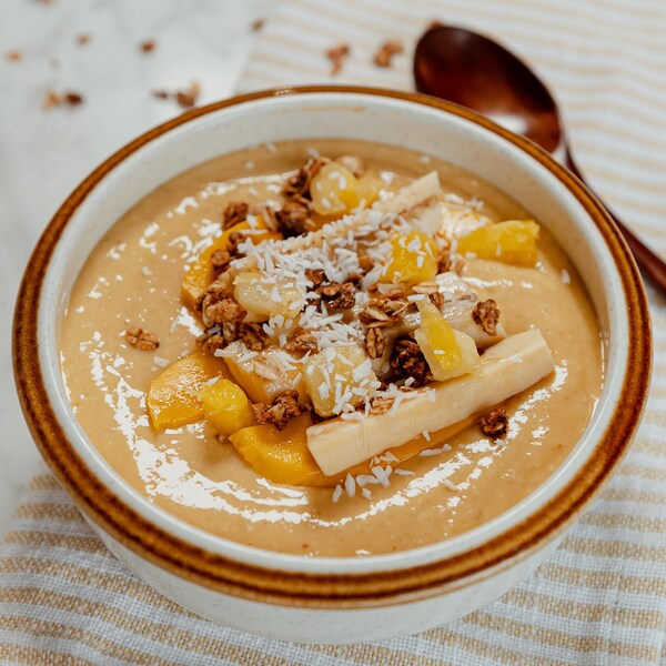 Un bol de smoothie garni de morceaux de bananes et de mangues.