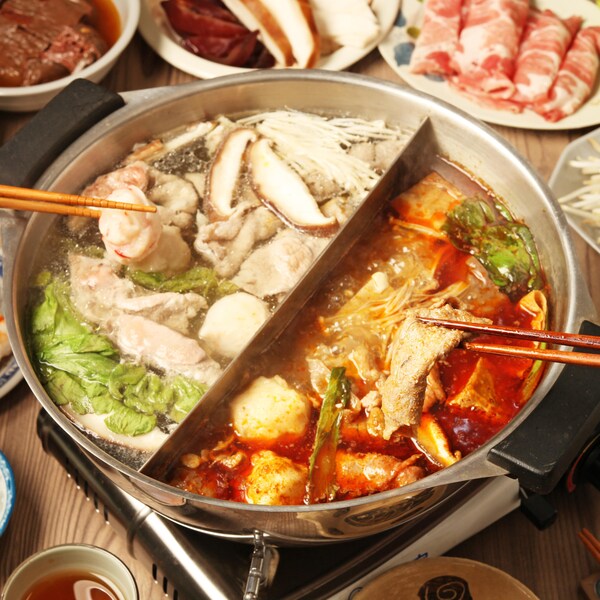 Des légumes et de la viande en train de cuire dans du bouillon à fondue chinoise.