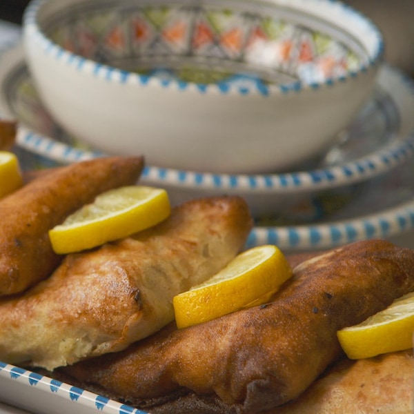 Quatres chaussons cuits et servis avec des tranches de citron dans une assiette.