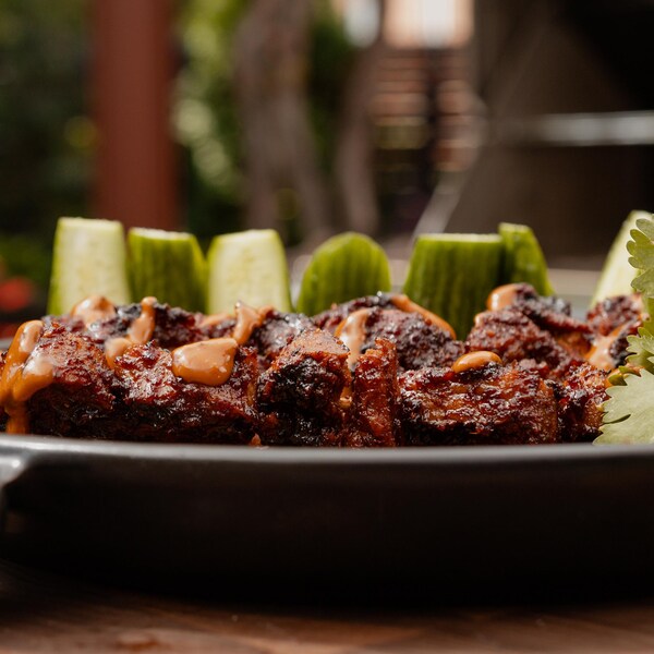 Une assiette avec des brochettes de satay de seitan avec ses garnitures.