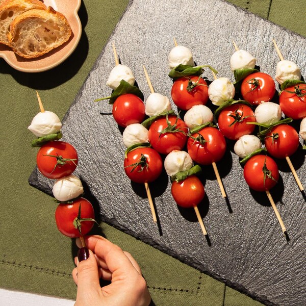 Des brochettes bocconcinis, tomates et basilic dans une assiette.