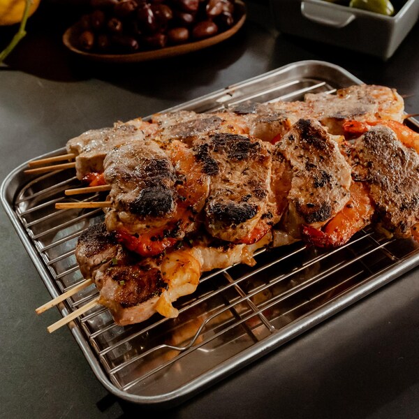 Des brochettes de porc et de crevettes sur une grille sortant du four.