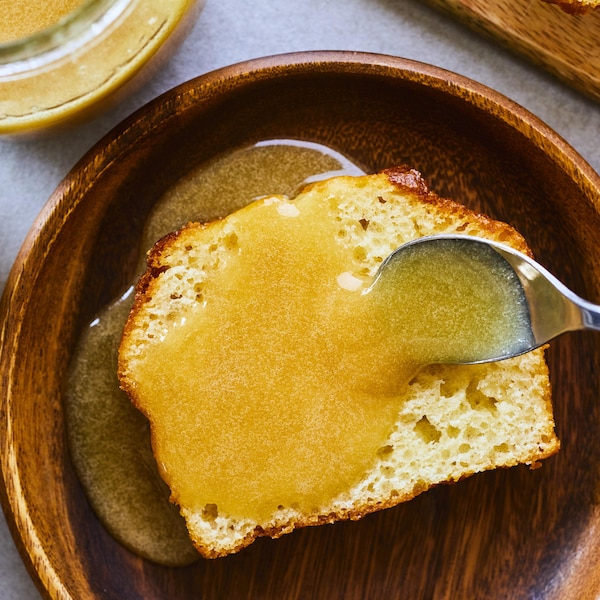 Cuillère qui verse du caramel sur une tranche de gâteau à la vanille dans une assiette.