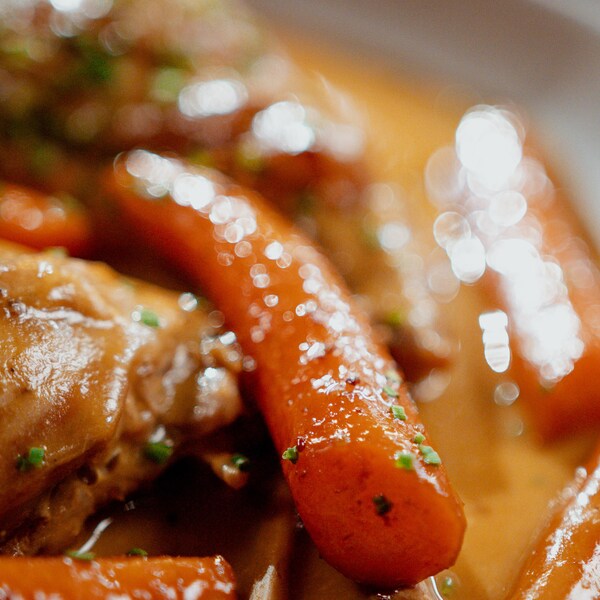 Des carottes cuites dans un bol avec des cuisses de lapin.