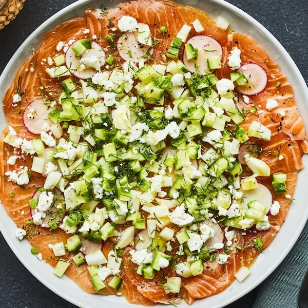 Une assiette de carpaccio de saumon garni de radis, de fenouil et de concombre.