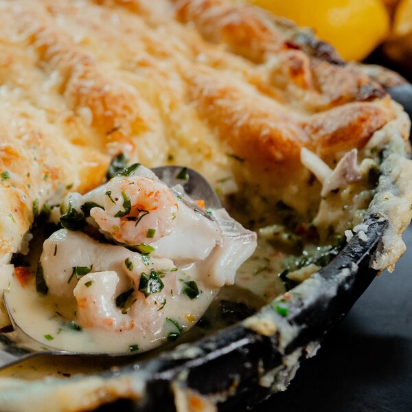 Une casserole de remplie de doré, de crevettes et de pommes de terre gratinés.