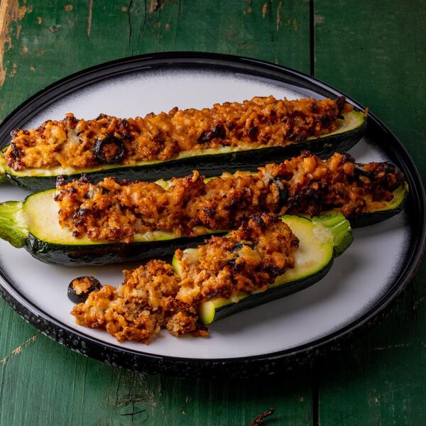Trois courgettes farcies dans une assiette.