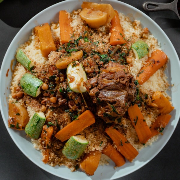 Une grande assiette ronde remplie de couscous à l'agneau.