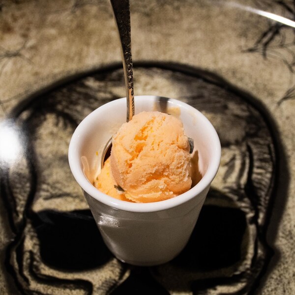 Un petit pot de crème glacée à l'orange et à la réglisse dans une assiette au thème de l'Halloween.