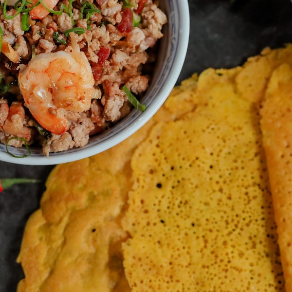 Une pile de crêpes croustillantes servies avec un bol de farce porc et crevettes.