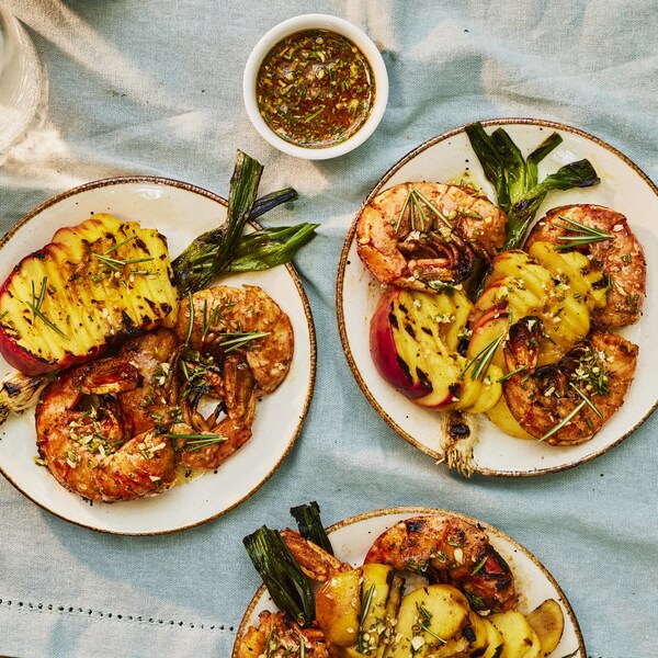 Des crevettes géantes dans une assiette avec des pêches grillées.