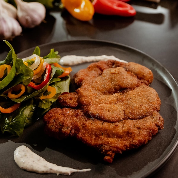 Une assiette d'escalopes de porc panées et de salade d'épinards.