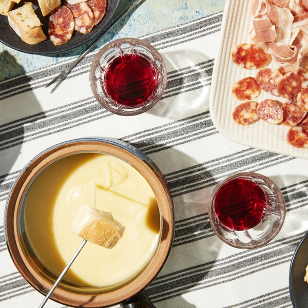 Une casserole de fondue au fromage accompagnée de plats de charcuteries.