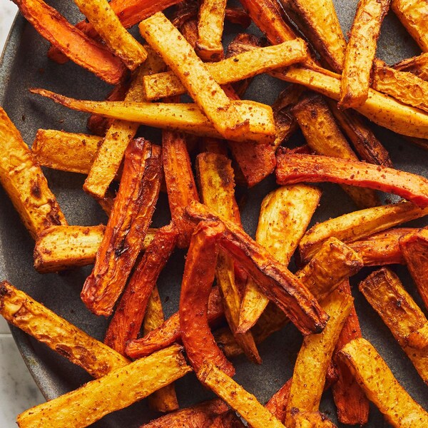 Des frites de légumes-racines dans une assiette noire sur un comptoir de cuisine. 