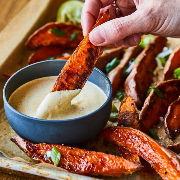 Des frites de patates douces qui sortent du four avec un petit bol de mayo au cari. 