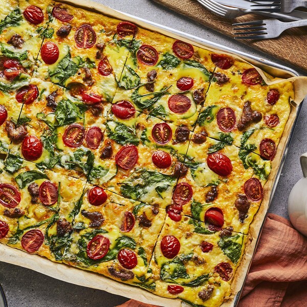 Une plaque de frittata est accompagnée de couverts et de deux tasses.