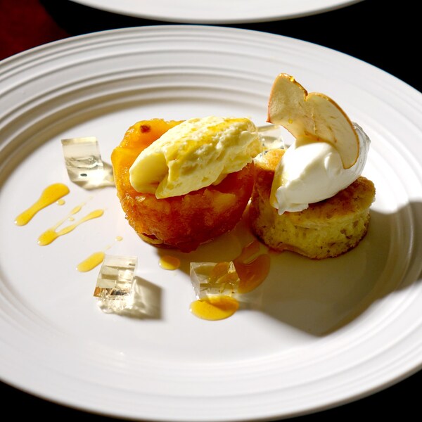 Un morceaux de gâteau dans une assiette avec de la mousse aux pommes et de la sauce au caramel.