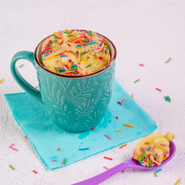 Un gâteau à la vanille dans une tasse avec des confettis sur le dessus.