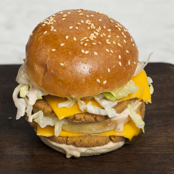 Deux hamburgers doubles végé servis sur une planche de bois.