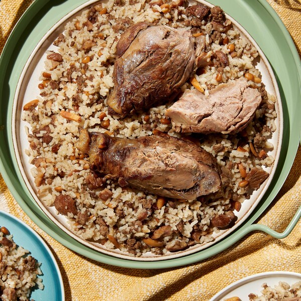 Du jarret de veau braisé servi sur un lit de riz contenant de la viande hachée, des noix torréfiées et des marrons grillés.