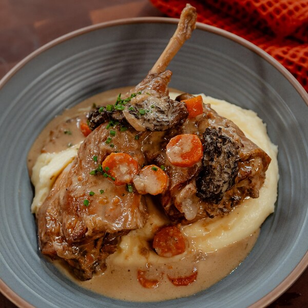 Du lapin à la crème et des légumes servis sur des pommes de terre en purée, dans un bol.