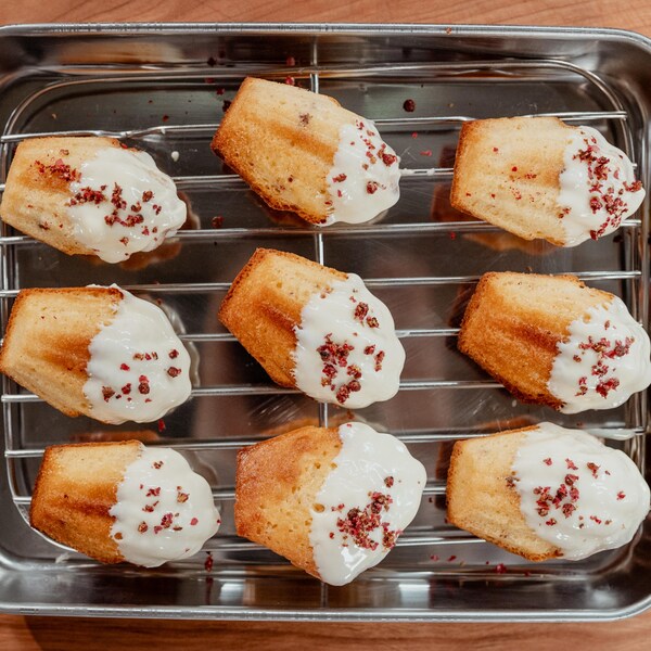 Neuf madeleines sur une grille garnies de chocolat blanc fondu.