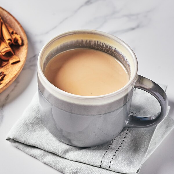 Une tasse de masala chai et une assiette en bois contenant des épices.