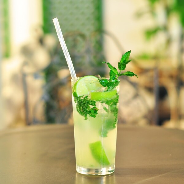 De la menthe, de la lime dans un grand verre de liquide avec une paille. 