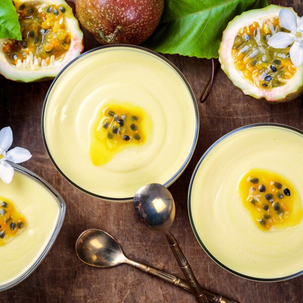 Sur un comptoir, il y a trois coupes en verre contenant de la mousse au fruit de la passion.