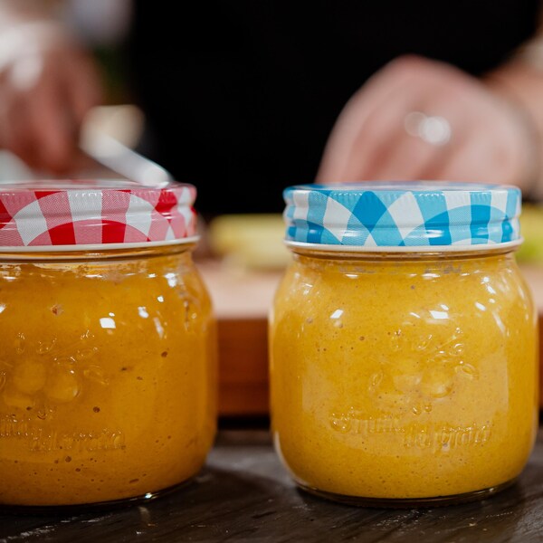 Trois pots Mason remplis de moutarde jaune.