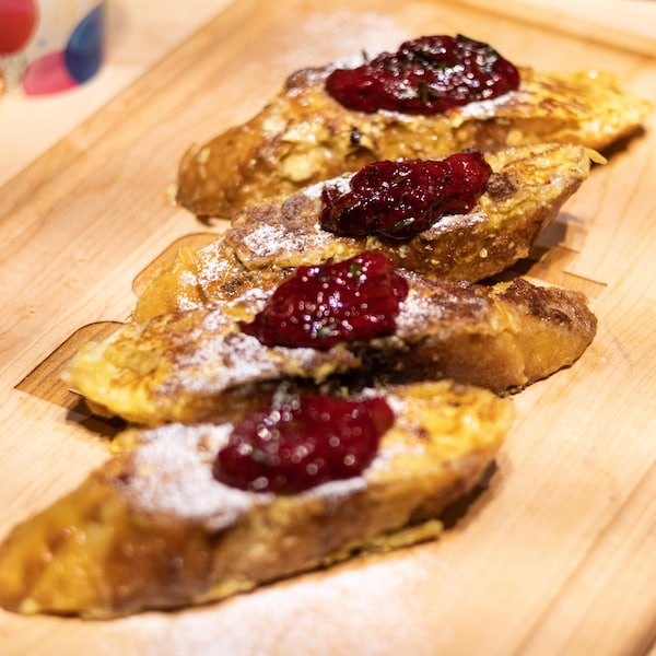 Des pains dorés avec de la compote aux petits fruits sur une planche à découper.