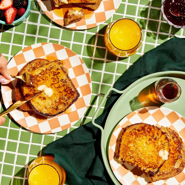 Du pain doré servi avec du sirop d'érable, de petits fruits frais, de la confiture et du beurre.
