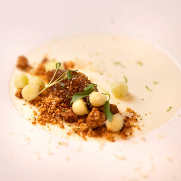 Une mousse crémeuse garnie d'un crumble et de noisettes entières, servie dans un bol évasé.