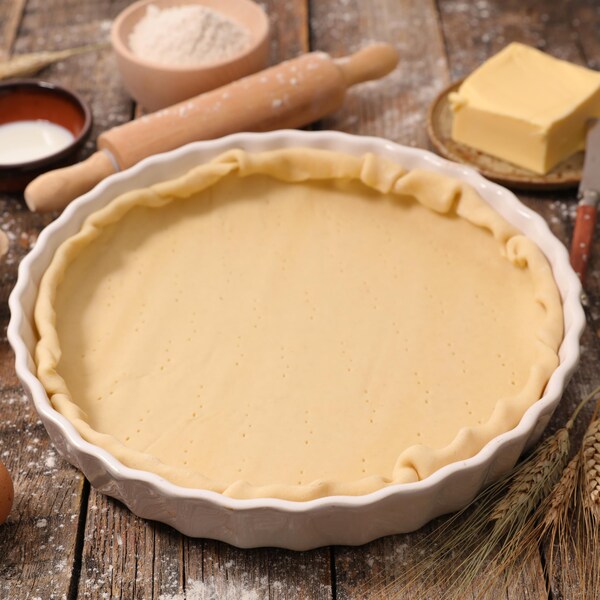 Une abaisse de pâte brisée dans un moule à tarte.