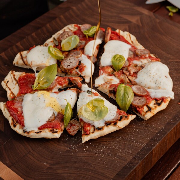 Une pizza cuite sur le barbecue sur une planche à découper.
