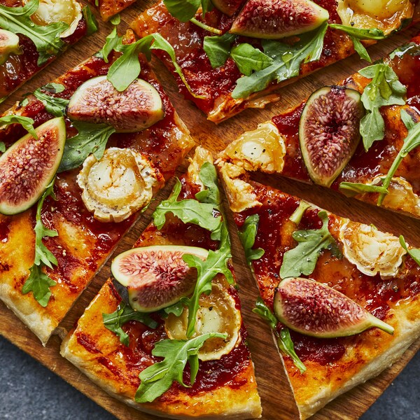 Une pizza aux figues et au fromage de chèvre sur une planche. 
