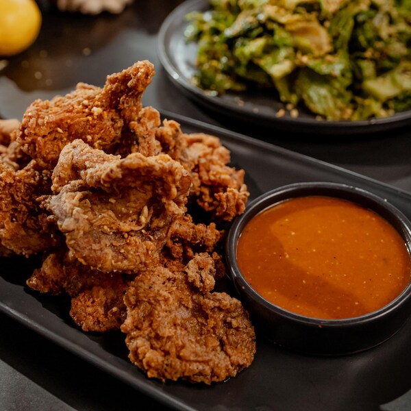 Des pleurotes frits avec un bol de sauce barbecue dans une assiette noire.