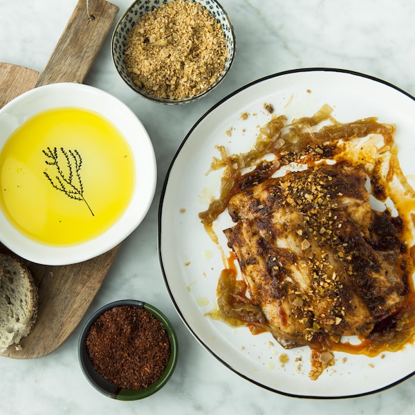 Une assiette de poisson rôti servi avec du pain et des condiments.