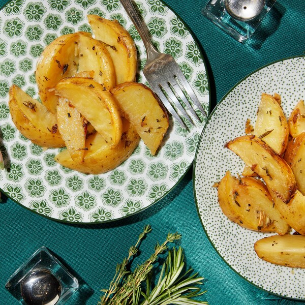 Des quartiers de pommes de terre rôties à la grecque dans des assiettes.