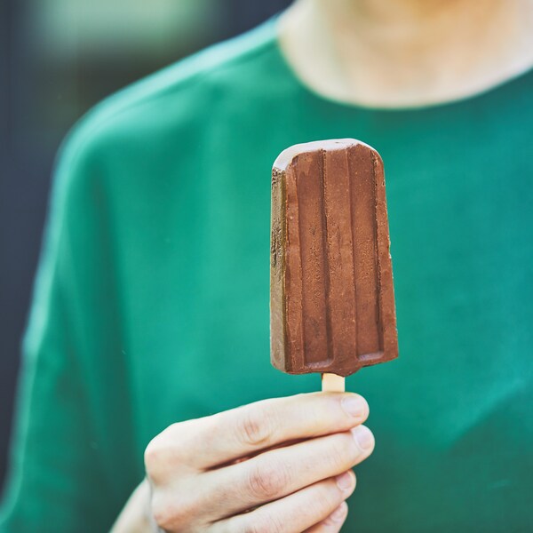 Main qui tient un pops glacé au chocolat.