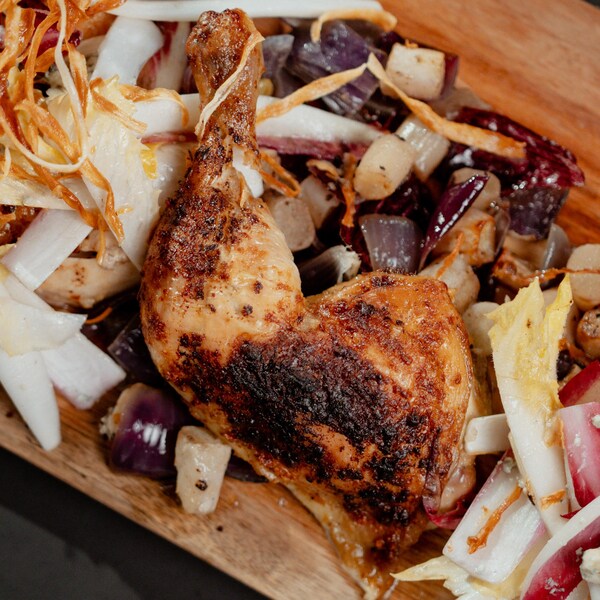 Un poulet en crapaudine placé sur une salade d'endives.