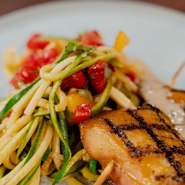 Une assiette de poulet grillé cari et soya avec linguine de courgettes.