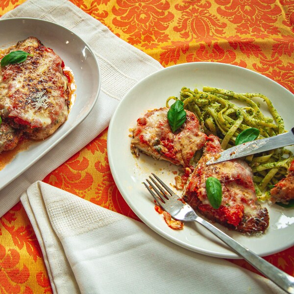 2 assiettes contenant des morceaux de poulet panés frits recouverts de sauce tomate et gratinés.