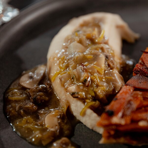 Une purée de haricots blancs dans une assiette avec une sauce aux champignons et une pointe de tarte tatin.