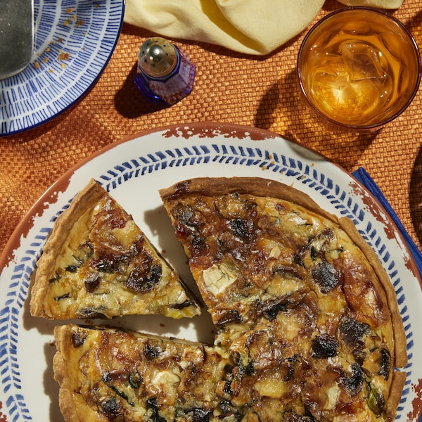 Une quiche aux champignons, poireaux, basilic et fromage de chèvre dans une assiette.